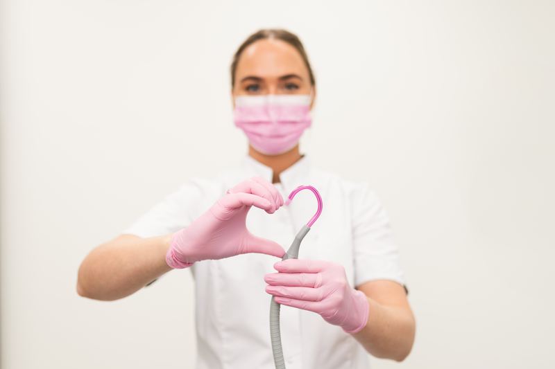 Mondhygiënist vormt met haar handen een hartje rond de afzuigslang